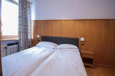 a bed with two pillows on it in a bedroom at Hotel Villa Alpina ***S in Cortina dʼAmpezzo