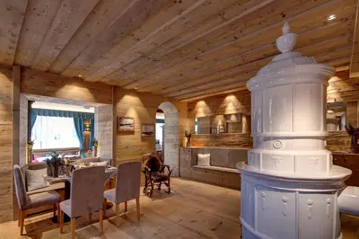 a living room with a wooden ceiling and a table and chairs at Hotel Villa Alpina ***S in Cortina dʼAmpezzo