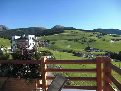 a view of a green hillside with a house and a fence at Pension Wiesenrain in Maranza
