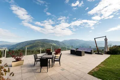 a patio with a table and chairs and mountains at Pension Wiesenrain in Maranza