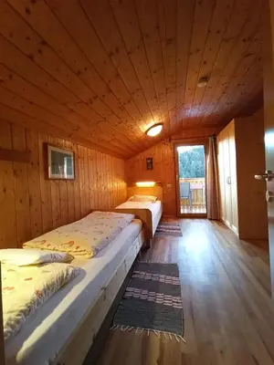 two beds in a room with wooden walls at Haus Bergfrieden in Castelrotto