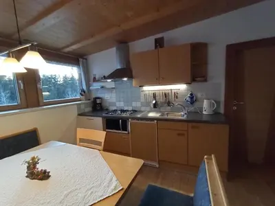 a kitchen with wooden cabinets and a table with a christmas tree at Haus Bergfrieden in Castelrotto