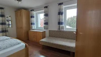 a bedroom with a bed and a window and a bench at Haus Bergfrieden in Castelrotto