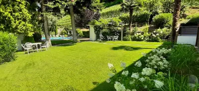a garden with a lawn with chairs and flowers at Agriturismo Sittnerhof in Merano