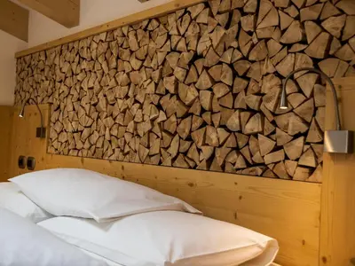 a bedroom with a stone wall and a bed with pillows at Hotel El Paster in Pozza di Fassa