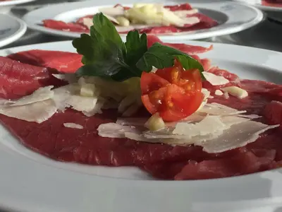 a plate of food with meat and tomatoes on it at Hotel El Paster in Pozza di Fassa