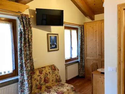 a living room with a chair and a television on the wall at Stella Alpina in Voltago