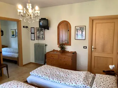 a bedroom with two beds and a dresser and a chandelier at Stella Alpina in Voltago