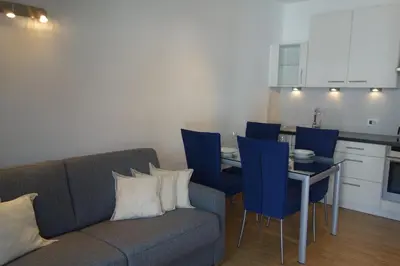 a living room with a couch and a table with blue chairs at Hager Apartment 2 in Merano