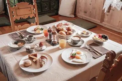 a table with plates of breakfast food on it at Hotel Genziana in Selva di Val Gardena