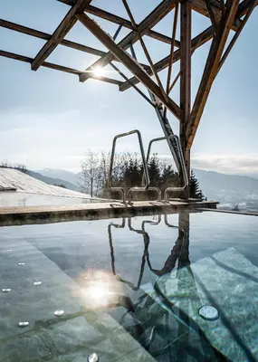 a swimming pool with the sun shining on the water at Parkhotel Holzerhof in Maranza