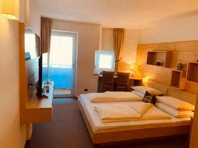 a hotel room with two beds and a dining room at Hotel Valpudra in Selva di Val Gardena