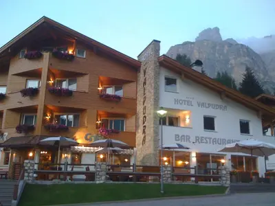 a hotel with umbrellas in front of a mountain at Hotel Valpudra in Selva di Val Gardena