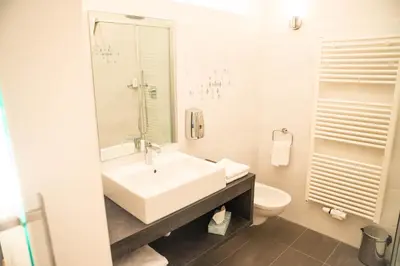a white bathroom with a sink and a toilet at Hotel Panoramik in Mühlbach