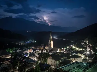 a lightning storm over a town at night at Hotel Panoramik in Mühlbach