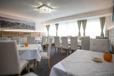 a dining room with white tables and white chairs at Hotel Panoramik in Mühlbach