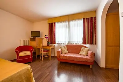 a white bed with a napkin with a horse on it at Hotel Alpino Al Cavalletto in Canazei