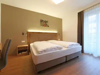 a bedroom with a bed and a large window at Residence Hotel Fever in Ortisei