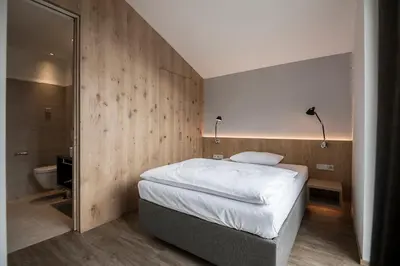 a bedroom with a large bed and a bathroom at Residence Hotel Fever in Ortisei