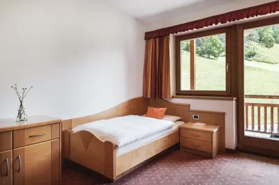 a small bedroom with a bed and a window at BergHotel Majarei in San Vigilio Di Marebbe