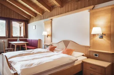a bedroom with a large bed and a table at BergHotel Majarei in San Vigilio Di Marebbe
