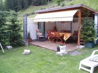 a wooden deck with a table and chairs on it at Garni Ortles in Selva di Val Gardena