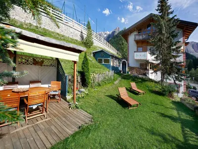 a patio with a table and chairs on a lawn at Garni Ortles in Selva di Val Gardena