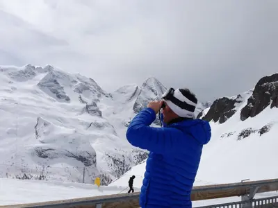 a man taking a picture of a snow covered mountain at Garni Ortles in Selva di Val Gardena