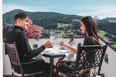 a man and woman sitting at a table with wine glasses at Hotel Residence Gasser in Villandro