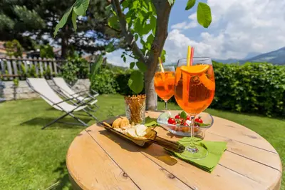 a wooden table with two glasses and a plate of food at Hotel Residence Gasser in Villandro