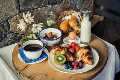 a table with a plate of food and a cup of coffee at Hotel Residence Gasser in Villandro