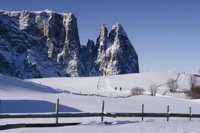 two people skiing in the snow in front of a mountain at Hotel Residence Gasser in Villandro