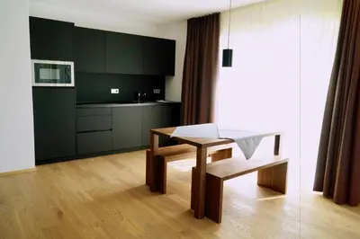a kitchen with a wooden table and a dining room at Residence Larciunei in Ortisei