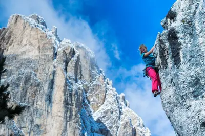 a woman is climbing on a rock mountain at Residence Larciunei in Ortisei