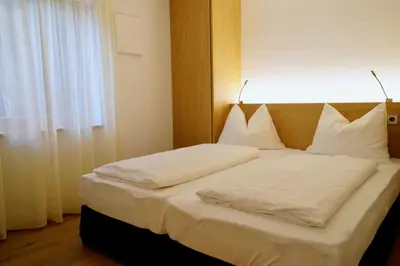 a bedroom with a bed with white sheets and a window at Residence Larciunei in Ortisei