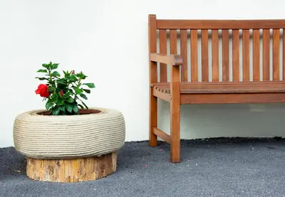 a wooden bench next to a pot with a red flower at Villa Gottfried B&B in Eggen