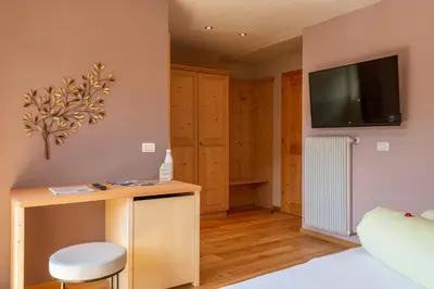 a bedroom with a desk and a tv on the wall at Villa Gottfried B&B in Eggen