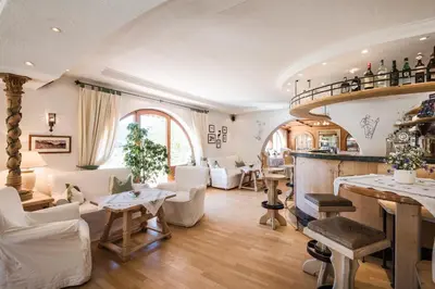 a living room with white furniture and a bar at Hotel Mareo Dolomites in San Vigilio Di Marebbe
