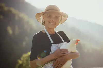 a woman wearing a hat holding a white chicken at Hotel Mareo Dolomites in San Vigilio Di Marebbe