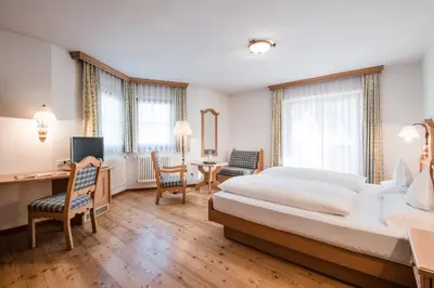 a hotel room with a large bed and a desk at Hotel Mareo Dolomites in San Vigilio Di Marebbe
