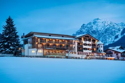 a large building with mountains in the background at Hotel Mareo Dolomites in San Vigilio Di Marebbe