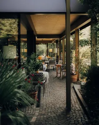 an outdoor patio with tables and chairs and plants at Boutique-Hotel Ballguthof am Golfplatz in Lana