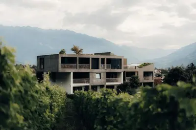 a house on a hill with mountains in the background at Boutique-Hotel Ballguthof am Golfplatz in Lana