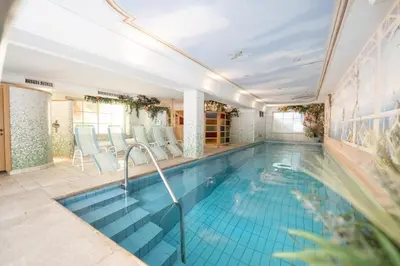 a swimming pool with blue chairs in a house at Piccolo - Dolomites & Gourmet Hotel in Selva di Val Gardena