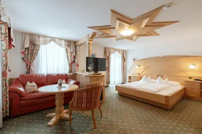 a hotel room with a bed and a couch and a table at Piccolo - Dolomites & Gourmet Hotel in Selva di Val Gardena