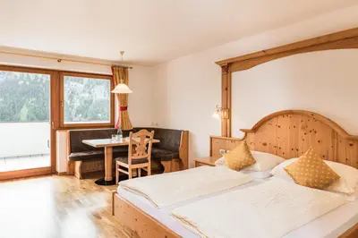 a bedroom with two beds and a desk and a table at Residence Rumanon in Ortisei