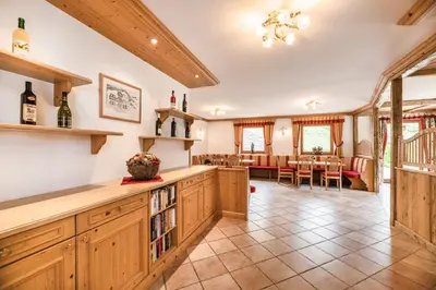 a large kitchen with wooden cabinets and a dining room at Residence Rumanon in Ortisei