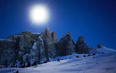 a moon over a snow covered mountain at night at Residence Rumanon in Ortisei