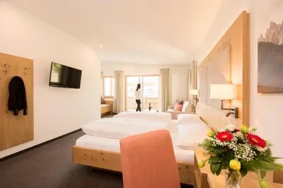 a hotel room with white furniture and a woman walking in the window at Panorama Hotel Flora in Villandro