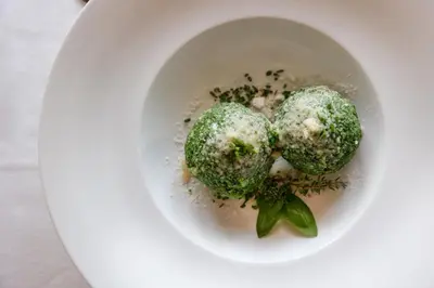 a white bowl filled with dumplings with herbs at Panorama Hotel Flora in Villandro